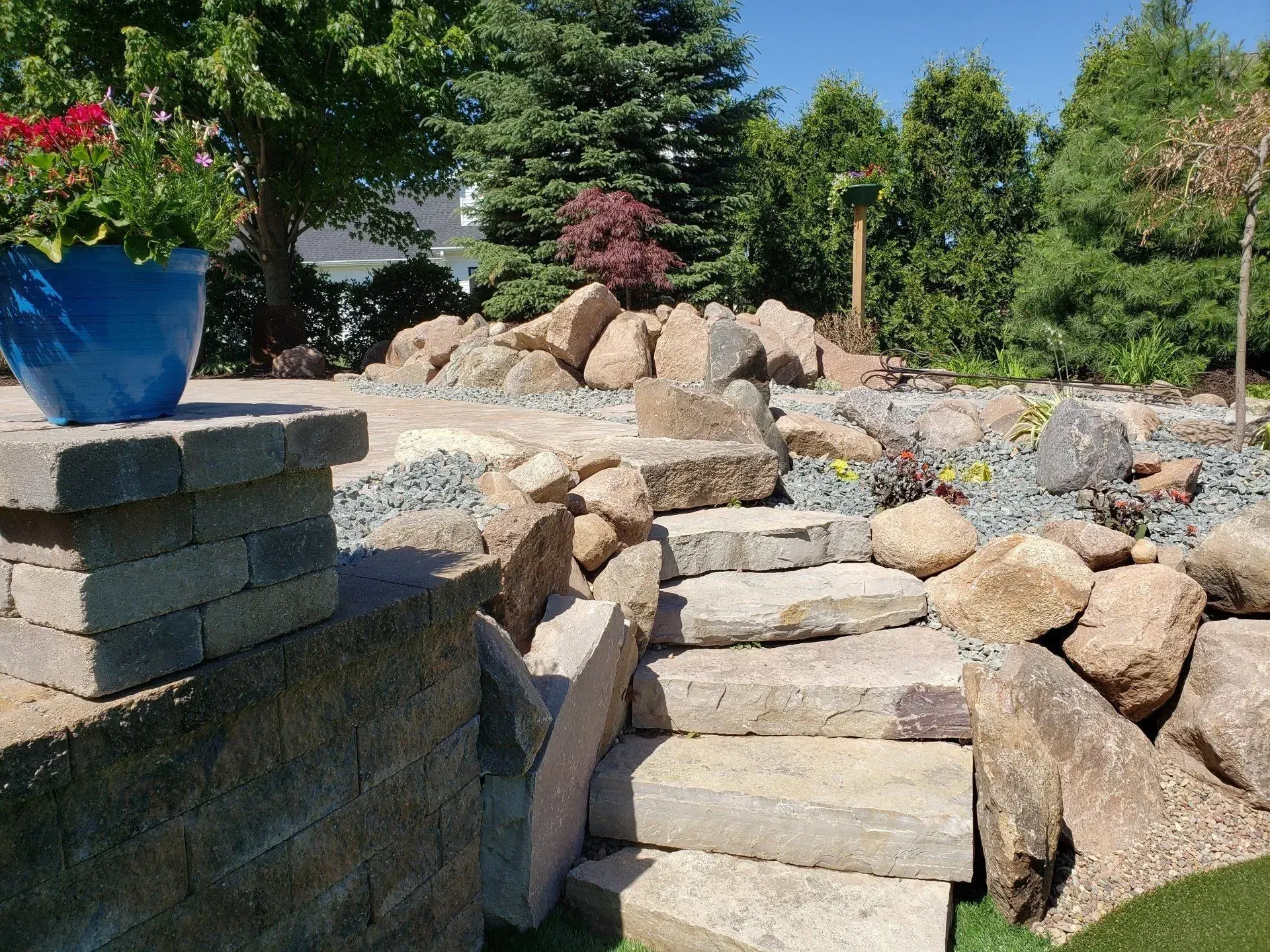 Tiered boulder retaining wall and rock garden above a block wall base