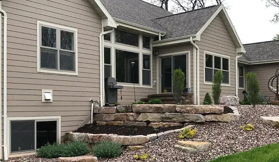 Low boulder retaining wall edging a mulched bed of young shrubs