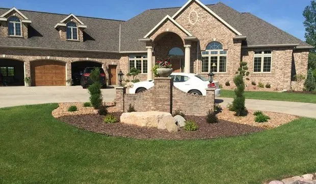 Brick home framed by mulched beds with accent boulders and young evergreens