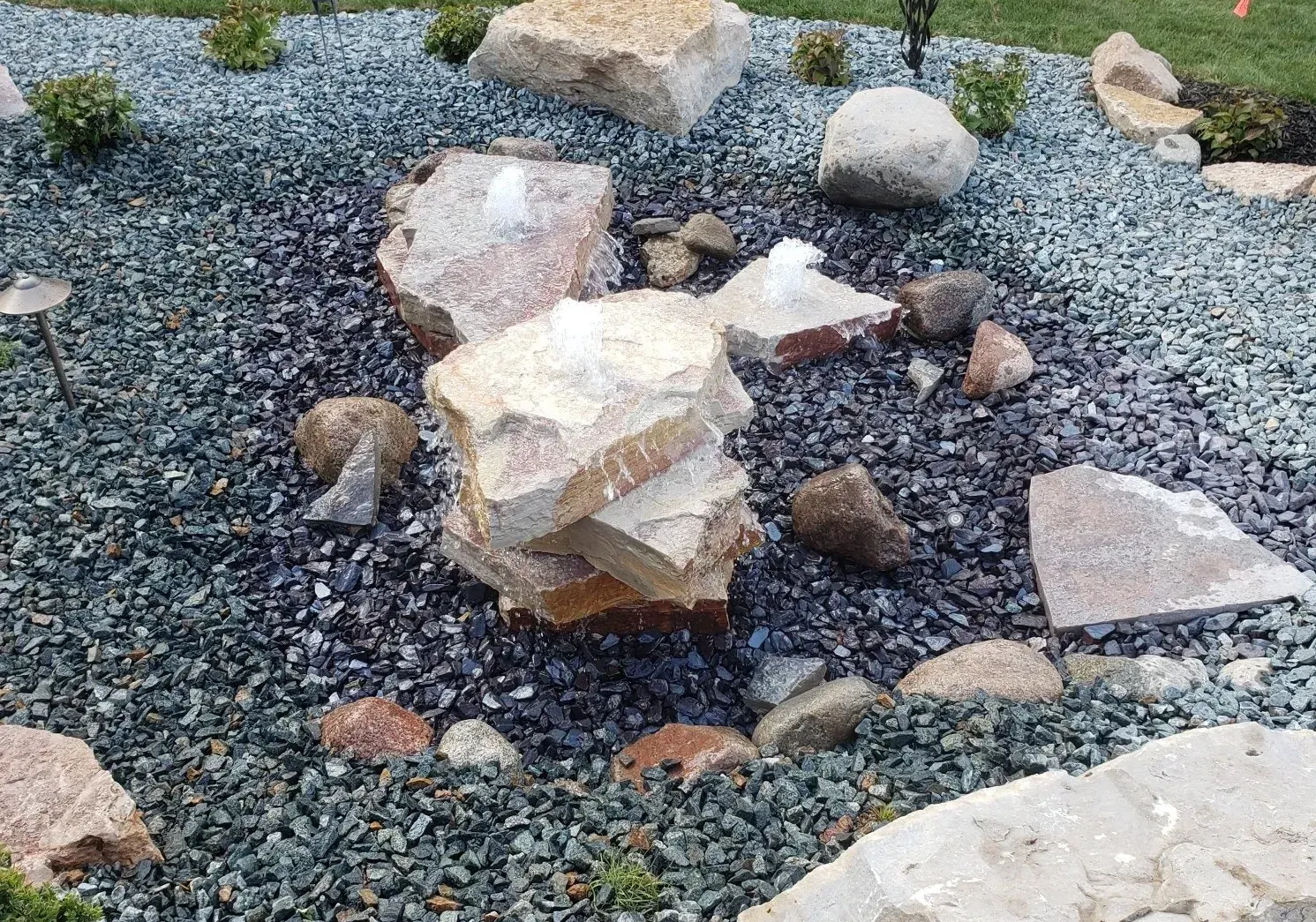 Bubbling boulder water feature set in a bed of decorative stone