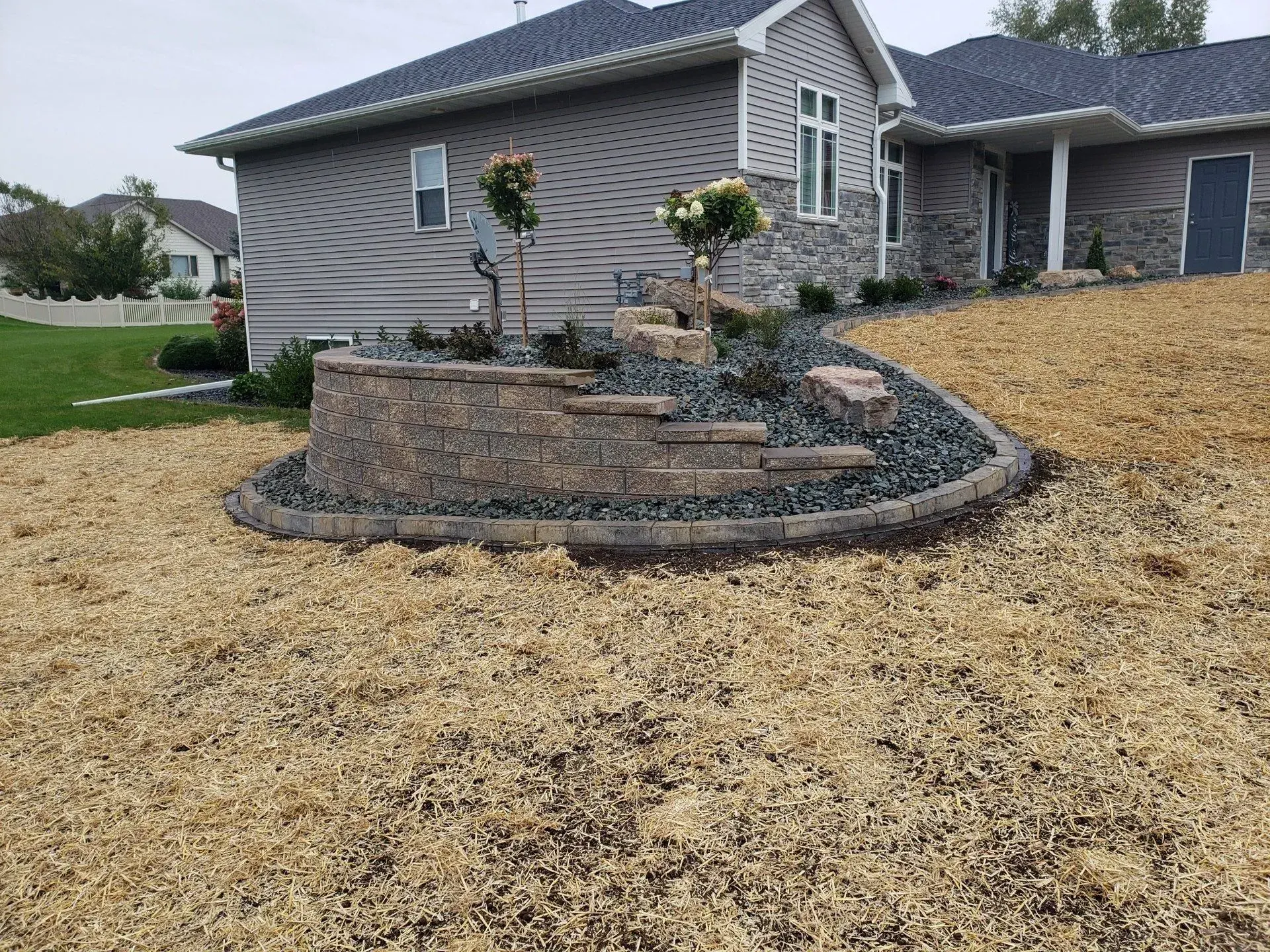 Curved segmental block retaining wall wrapping a new landscape bed