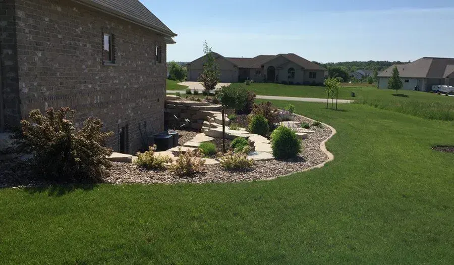 Curved concrete walkway winding between mulched beds and a trimmed lawn