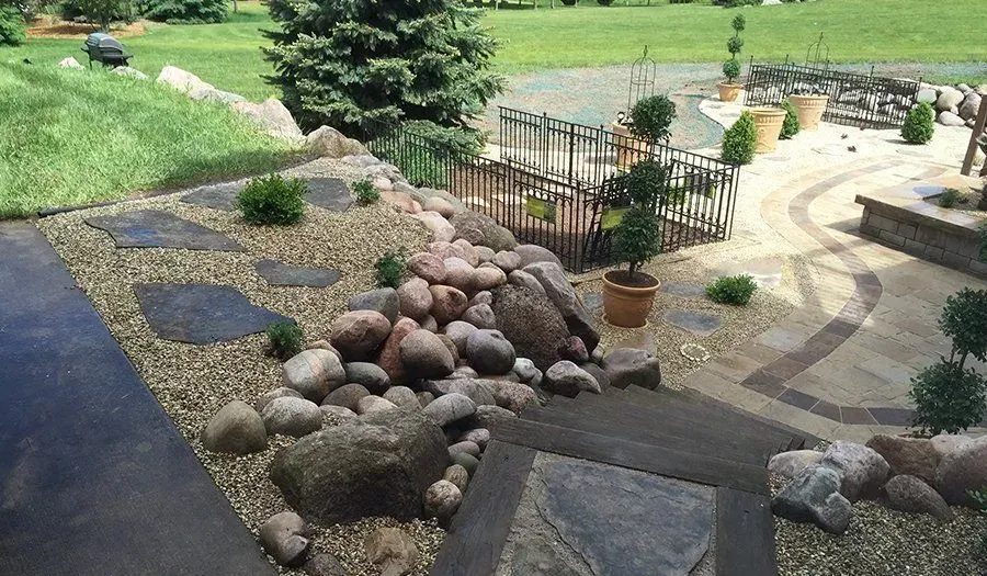 Fieldstone rock garden with a flagstone path and clipped topiaries in pots
