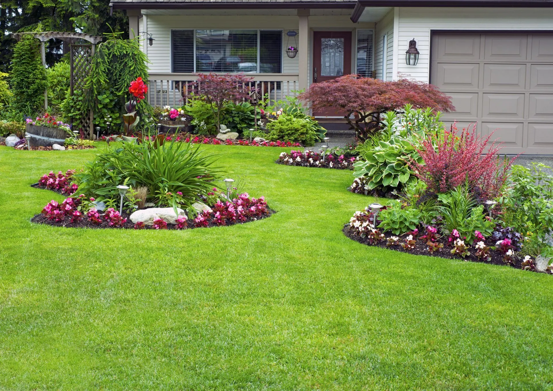 Front yard island bed of annuals and shrubs set in a mowed lawn