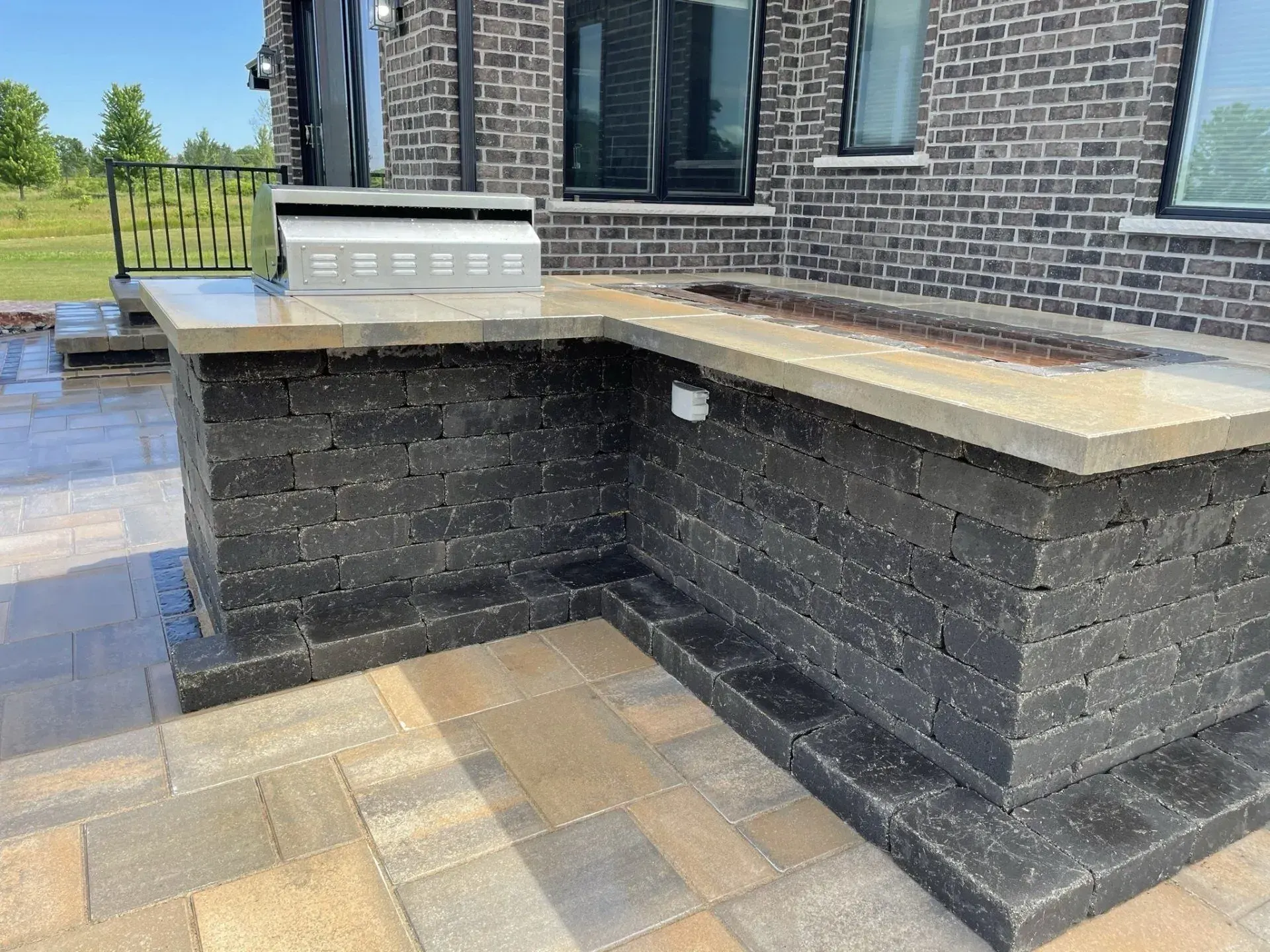 L-shaped outdoor kitchen counter under construction on a paver patio