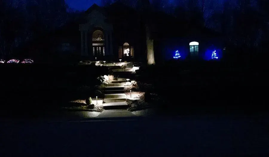Nighttime view of a lit entryway with uplit columns and illuminated steps