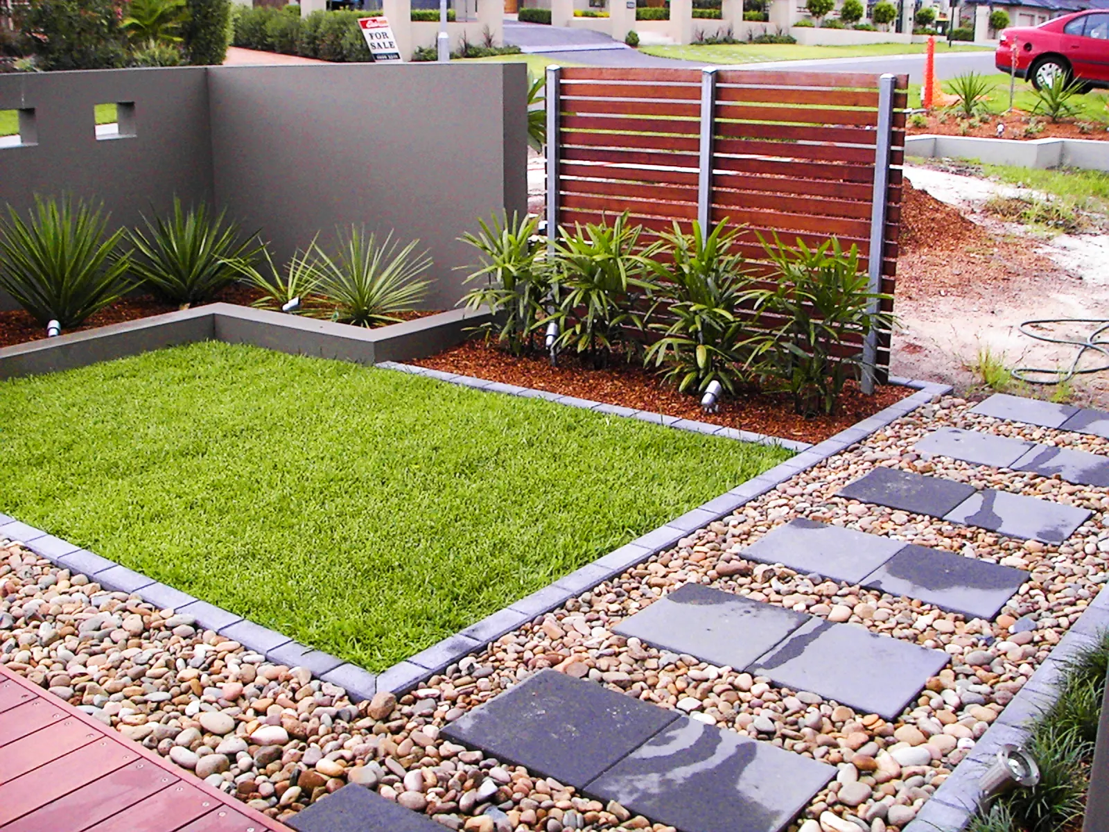Modern landscape with a clipped lawn, stone pavers and a slatted privacy screen
