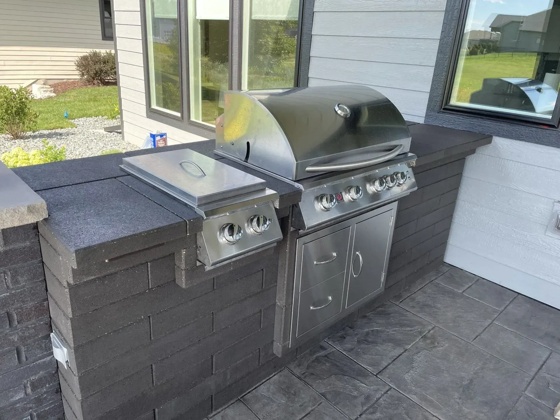 Outdoor kitchen with two stainless grills set into a dark stone counter