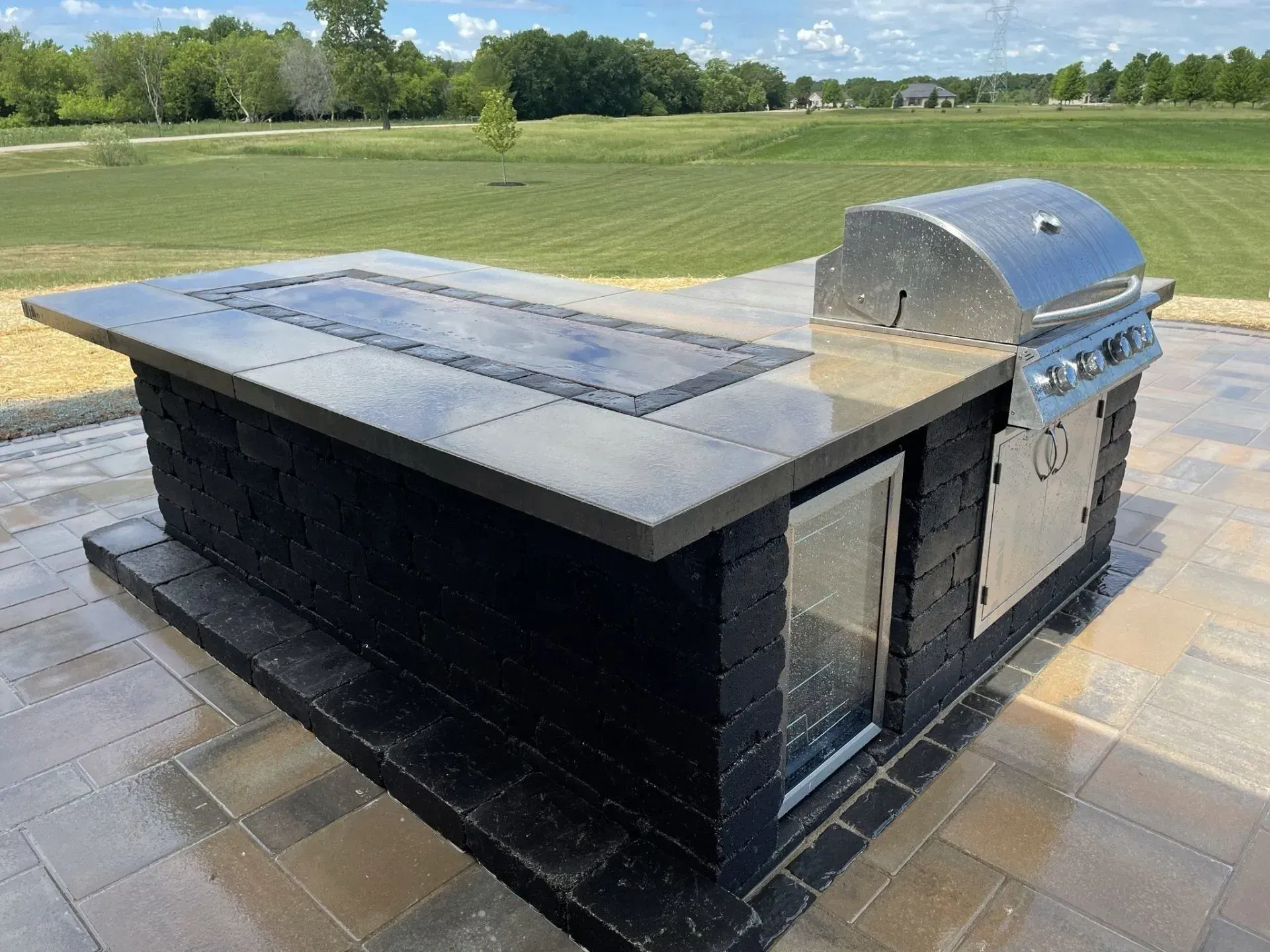 Outdoor kitchen island with a built-in grill overlooking open countryside