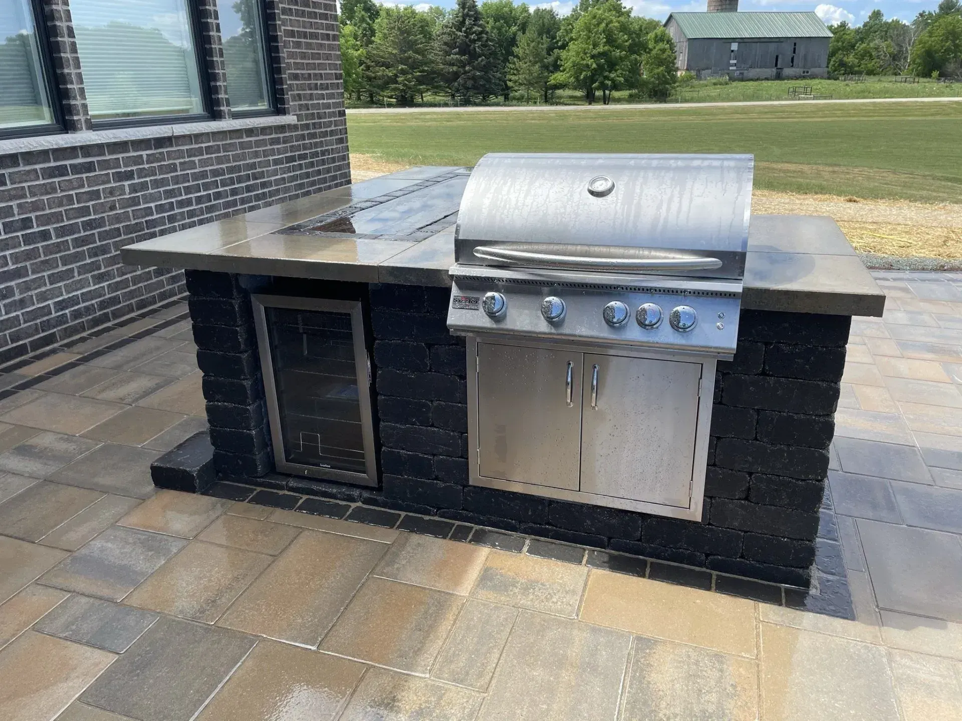 Dark stone outdoor kitchen with a stainless built-in grill and storage doors
