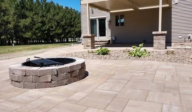 Paver patio with a raised stone fire pit under a covered porch