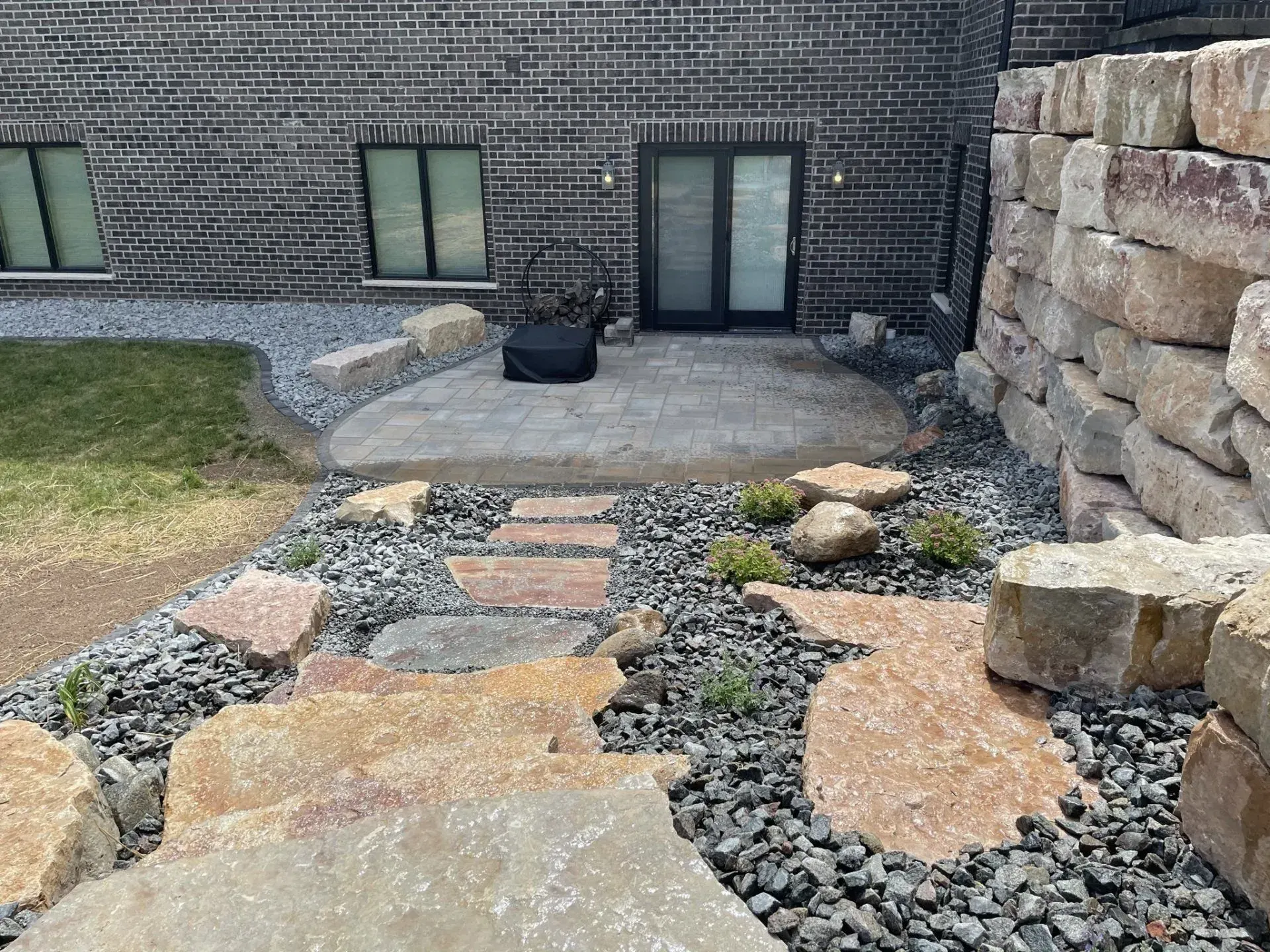 River rock bed with boulders and flagstone stepping stones leading to a patio door