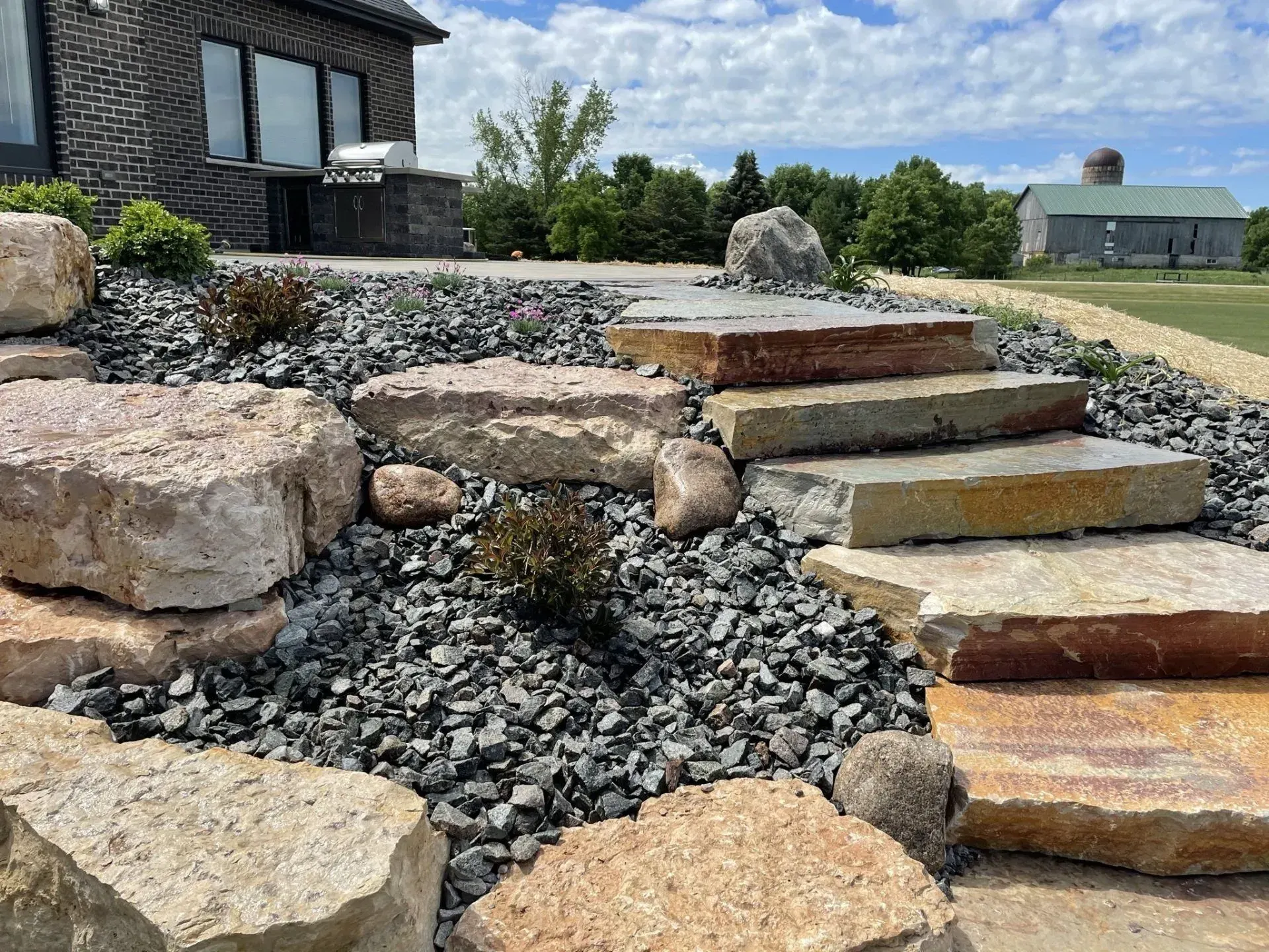 Stone slab steps climbing a boulder rock garden between river rock beds